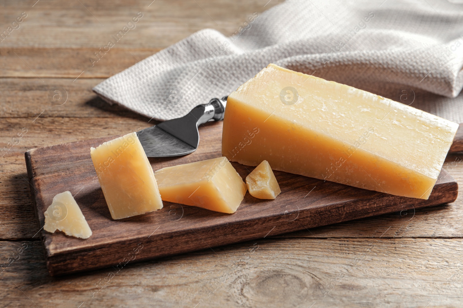 Photo of Board with cut Parmesan cheese on wooden table