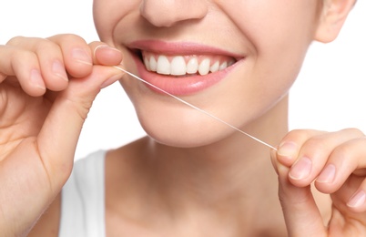 Photo of Young woman flossing her teeth on white background, closeup