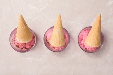 Photo of Flat lay composition with pink ice cream in wafer cones on light table