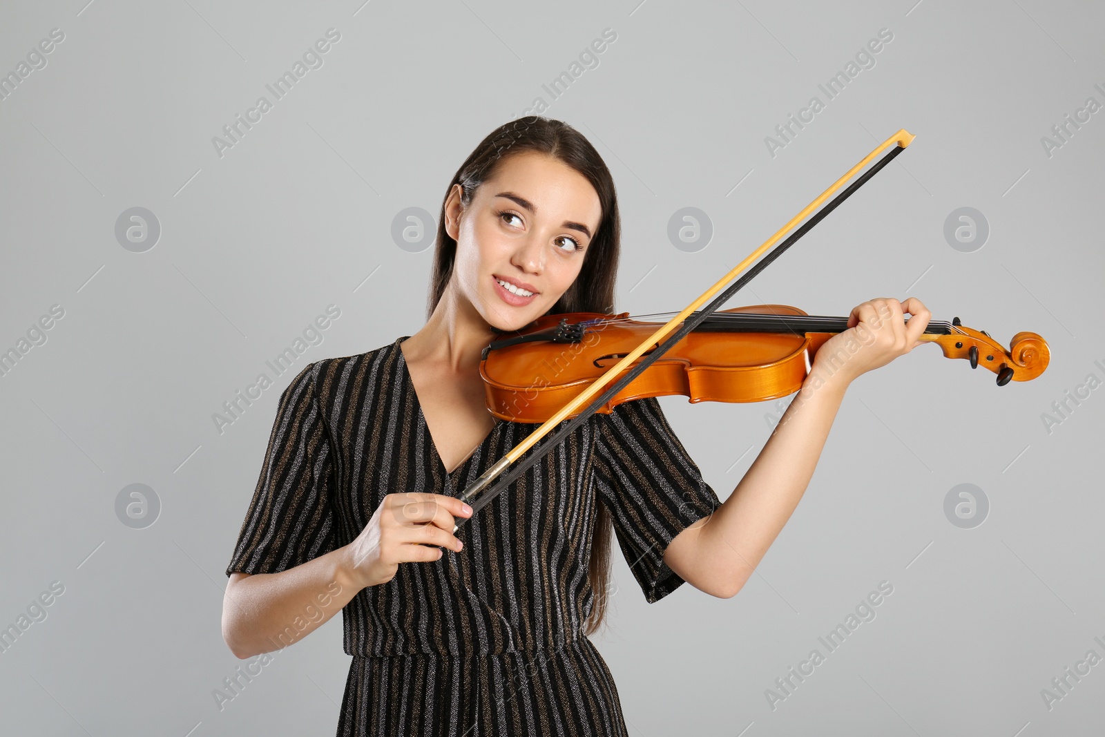 Photo of Beautiful woman playing violin on grey background