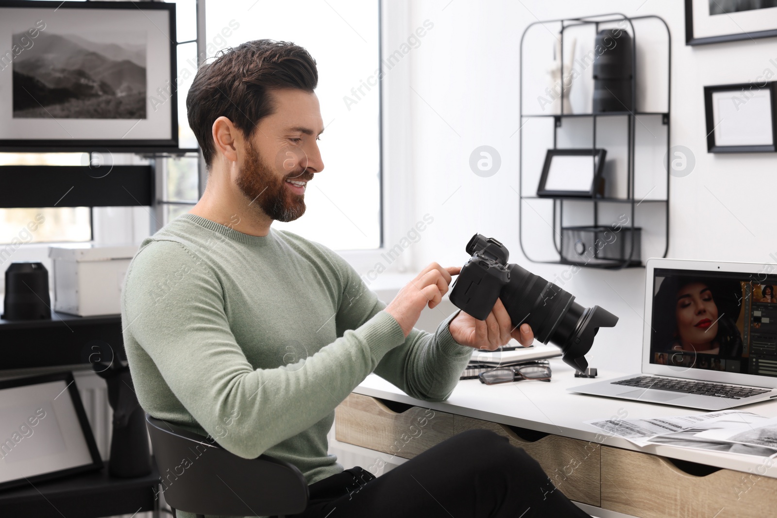 Photo of Professional photographer with digital camera at table in office