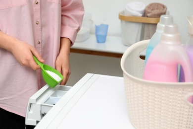 Photo of Woman pouring powder into drawer of washing machine in laundry room, closeup