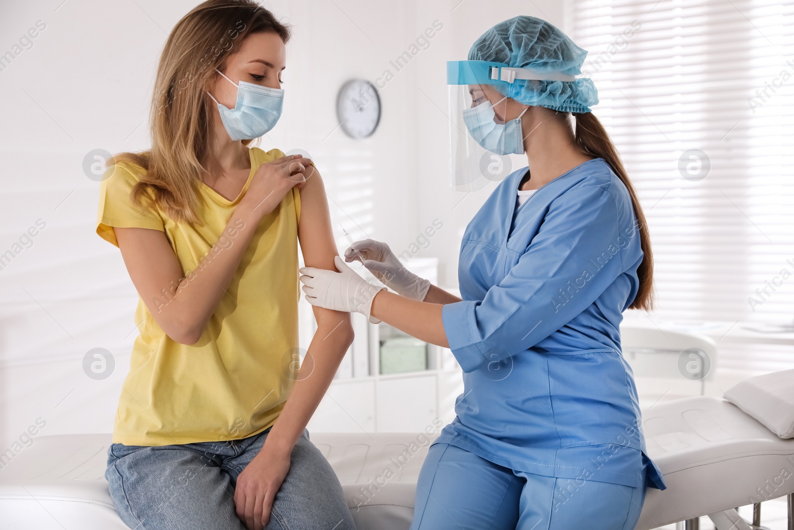 Photo of Doctor vaccinating young woman against Covid-19 in clinic