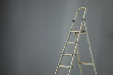 Photo of Metal stepladder on grey background. Space for text