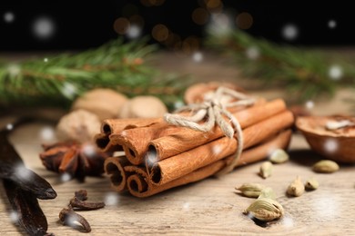 Image of Different spices and fir tree branches on wooden table, closeup. Cinnamon, cloves, anise, cardamom, vanilla, nutmegs