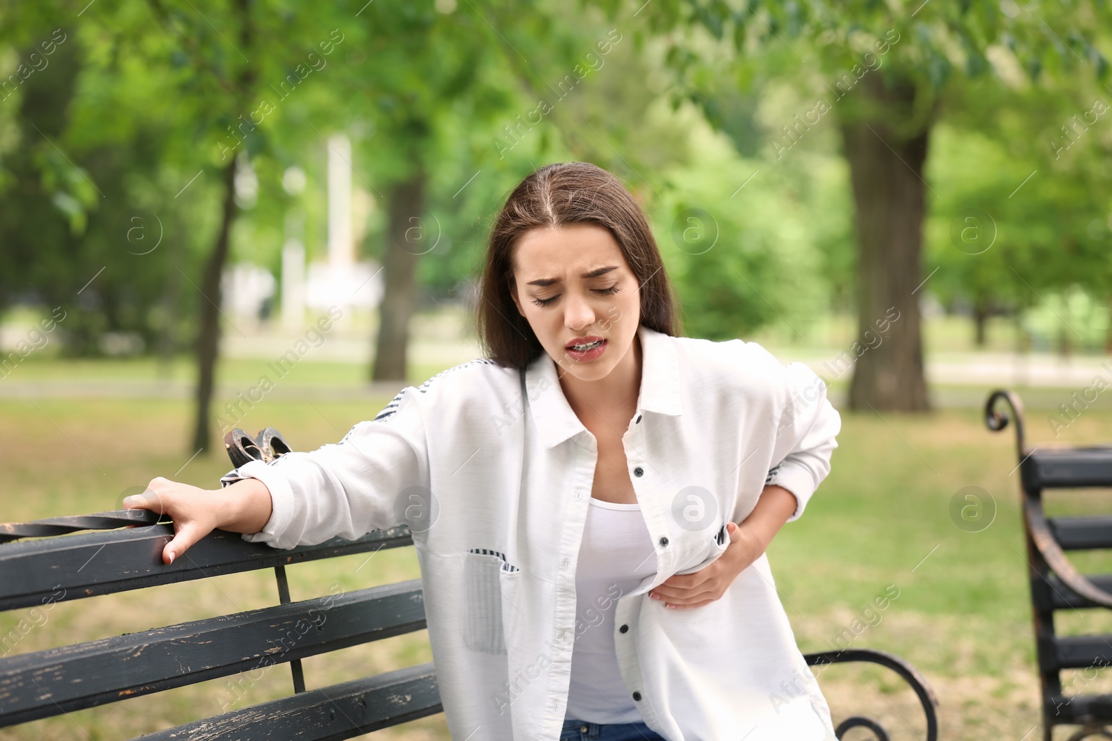 Photo of Young woman having chest pain in park. Heart attack