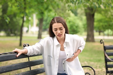 Young woman having chest pain in park. Heart attack