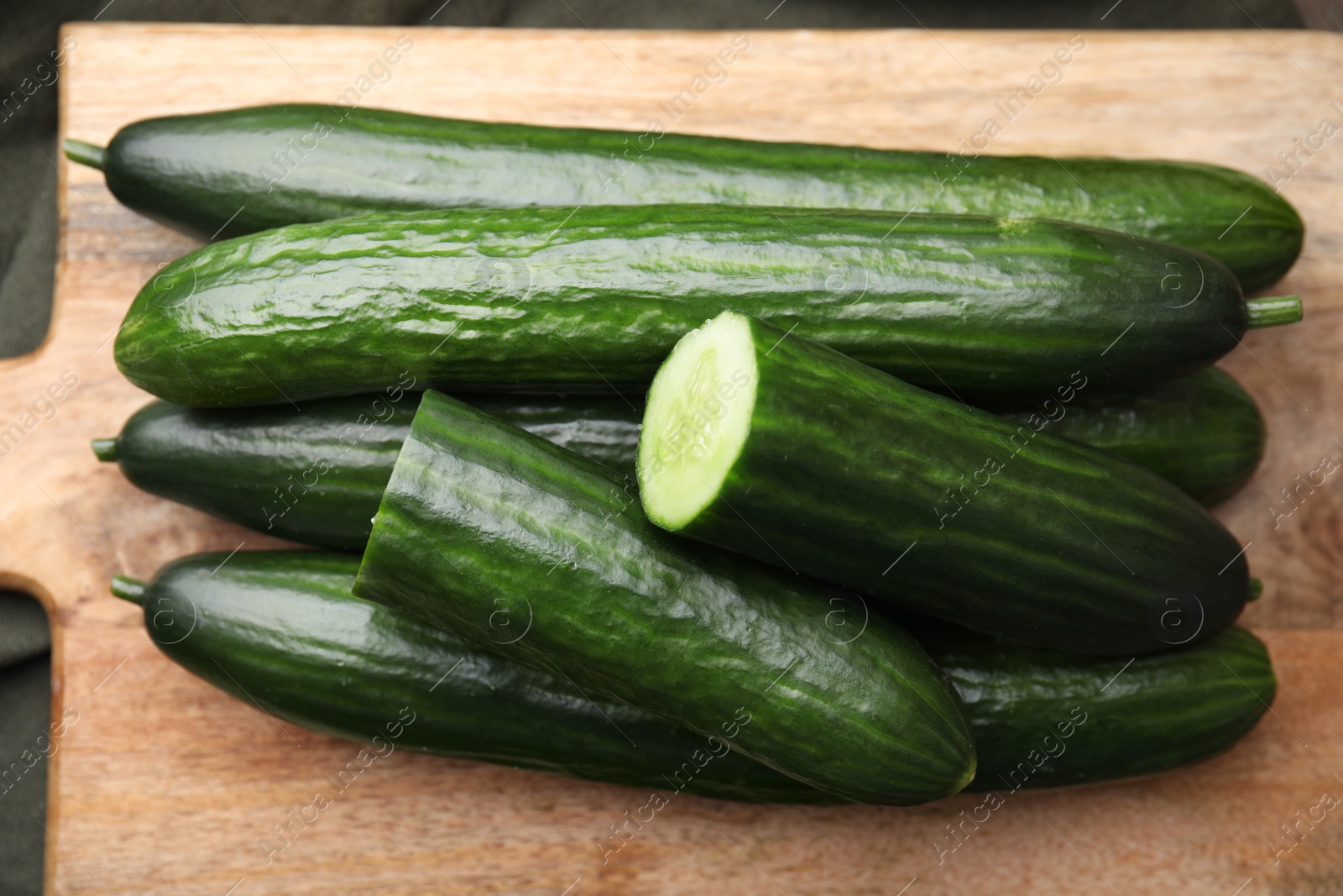 Photo of Fresh cucumbers on wooden board, above view