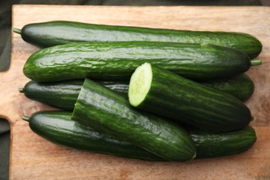 Photo of Fresh cucumbers on wooden board, above view