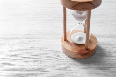 Photo of Hourglass with flowing sand on light wooden background. Time management