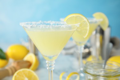 Photo of Delicious bee's knees cocktail on table against light blue background, closeup