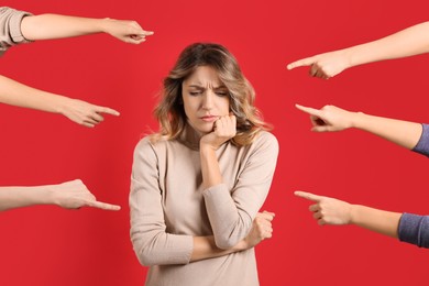 Photo of Stressed woman feeling uncomfortable because of people pointing at her against red background. Social responsibility concept