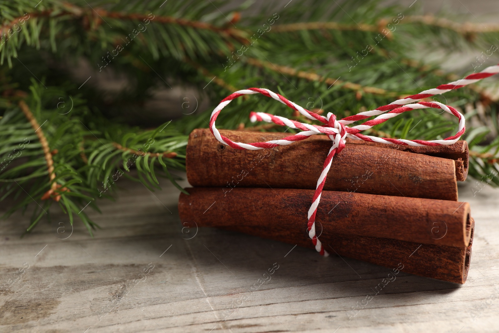 Photo of Cinnamon sticks and fir branches on wooden table, closeup