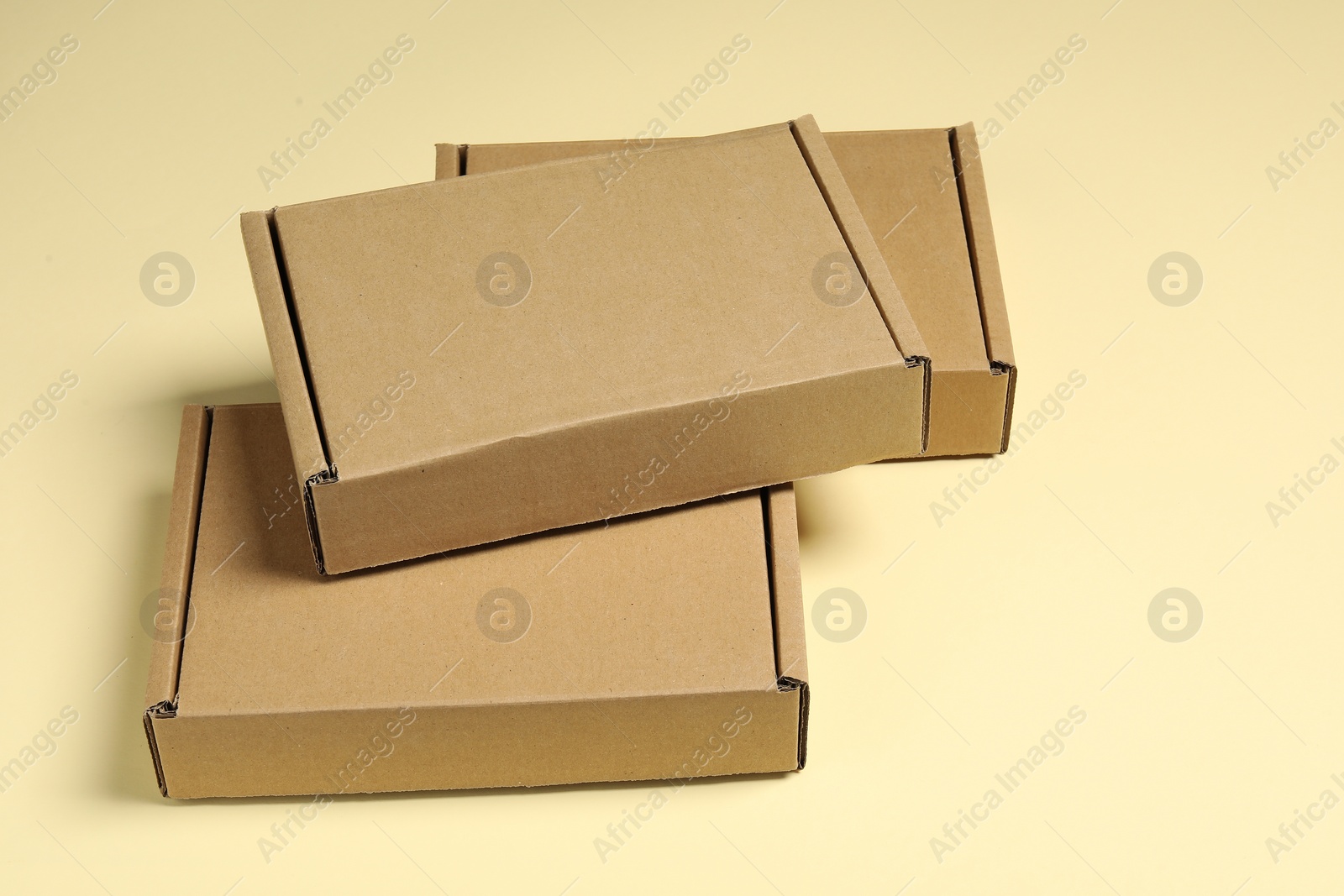 Photo of Many closed cardboard boxes on pale yellow background