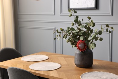 Photo of Vase with plants on wooden table in stylish dining room