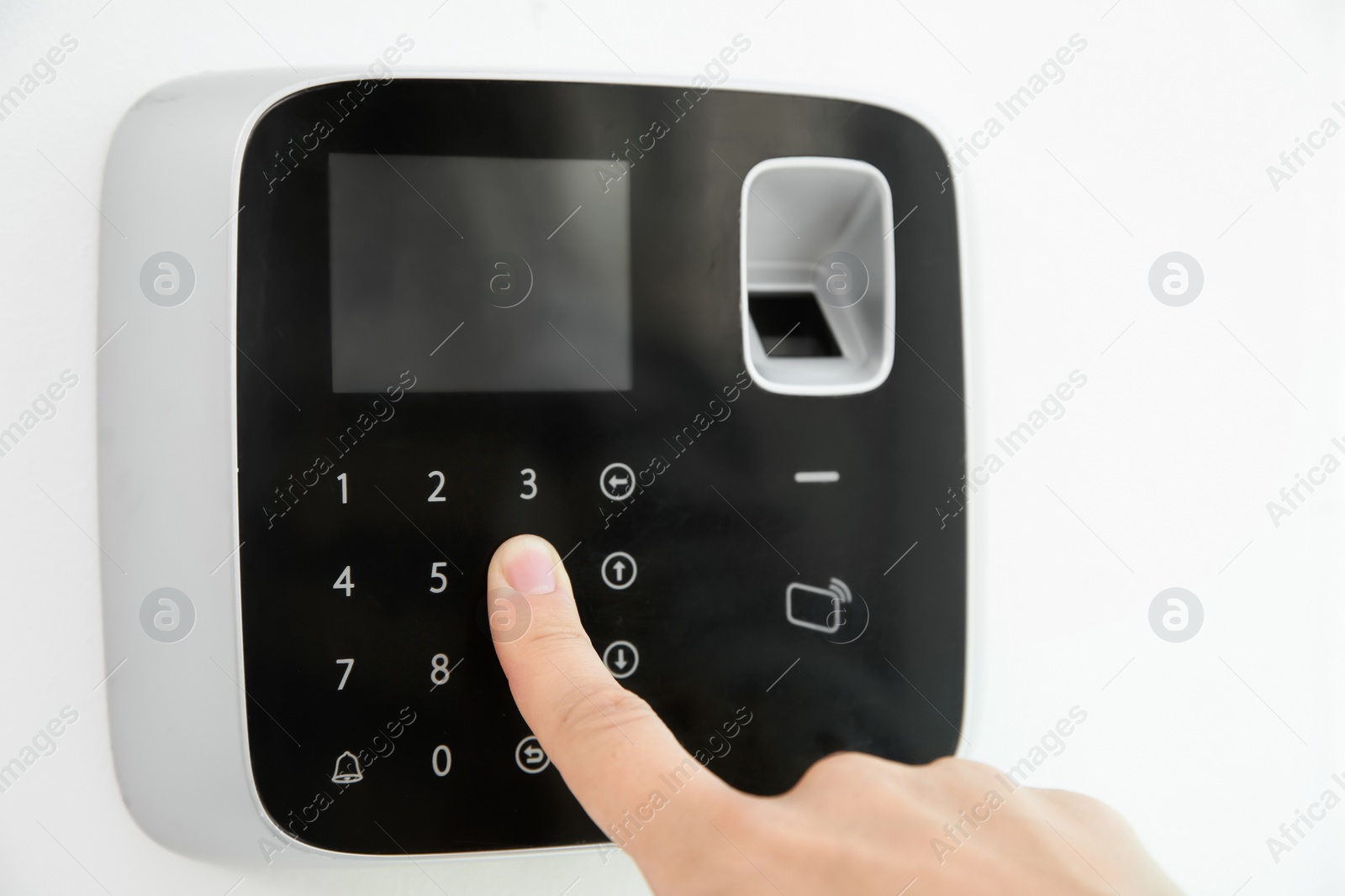 Photo of Young woman entering code on alarm system keypad indoors