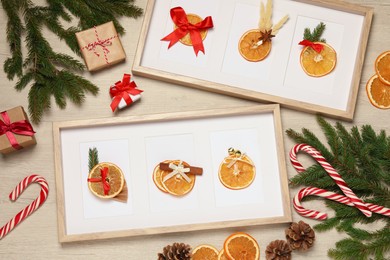 Photo of Flat lay composition of beautiful frames with dry orange slices decorated for Christmas on wooden table
