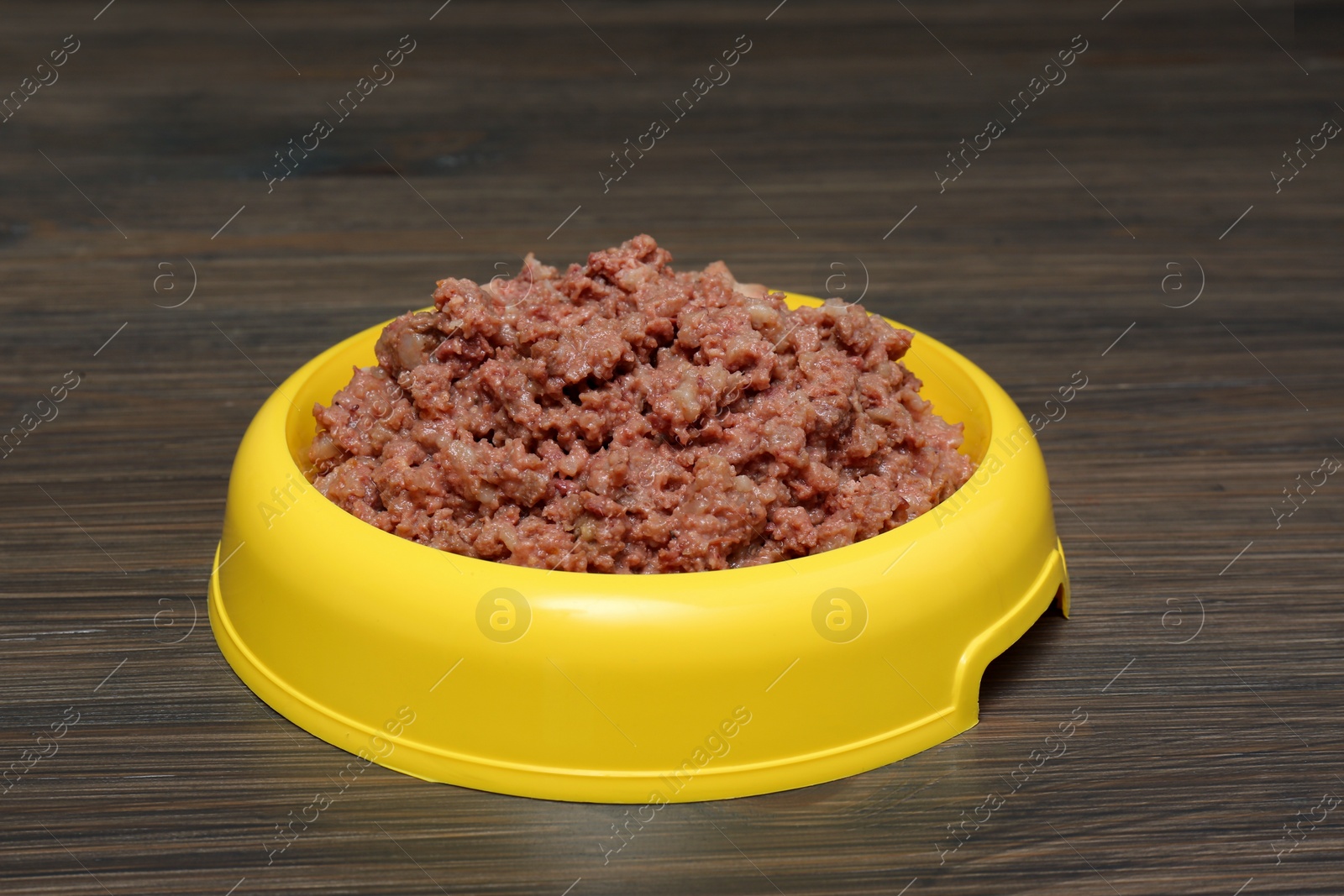 Photo of Wet pet food in feeding bowl on wooden background