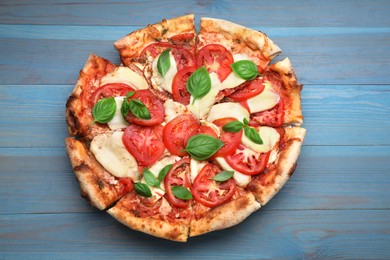 Photo of Delicious Caprese pizza on blue wooden table, top view