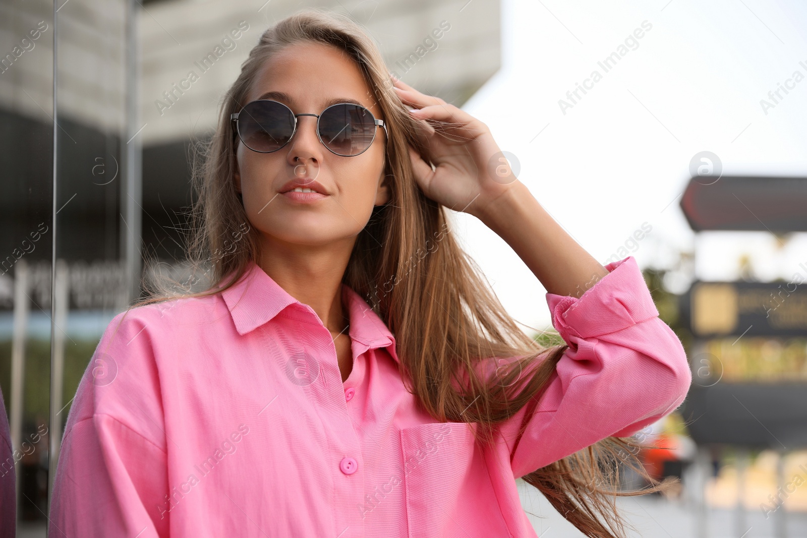 Photo of Beautiful young woman in stylish sunglasses on city street