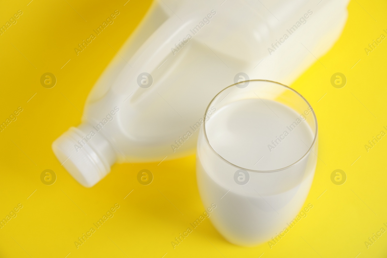 Photo of Gallon bottle and glass of milk on yellow background