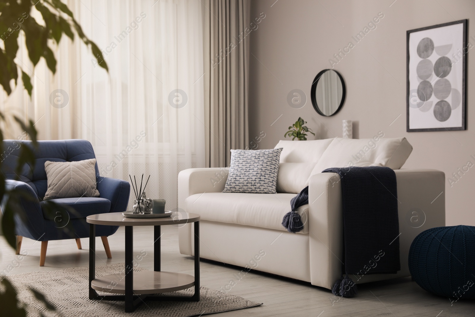 Photo of Stylish living room interior with white sofa, armchair and small coffee table