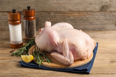 Photo of Fresh raw chicken with spices and lemon on wooden table
