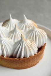 Tartlet with meringue on white plate, closeup. Delicious dessert