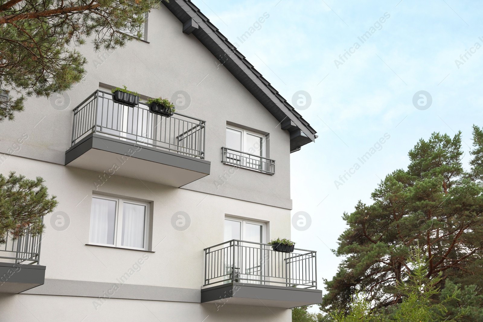 Photo of Beautiful beach house with balconies and trees outdoors