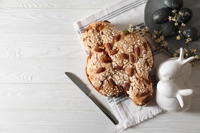 Delicious Italian Easter dove cake (Colomba di Pasqua), decorated eggs and bunny figures on white wooden table, flat lay. Space for text