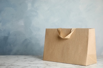 Photo of Paper shopping bag on table against color background. Mock up for design