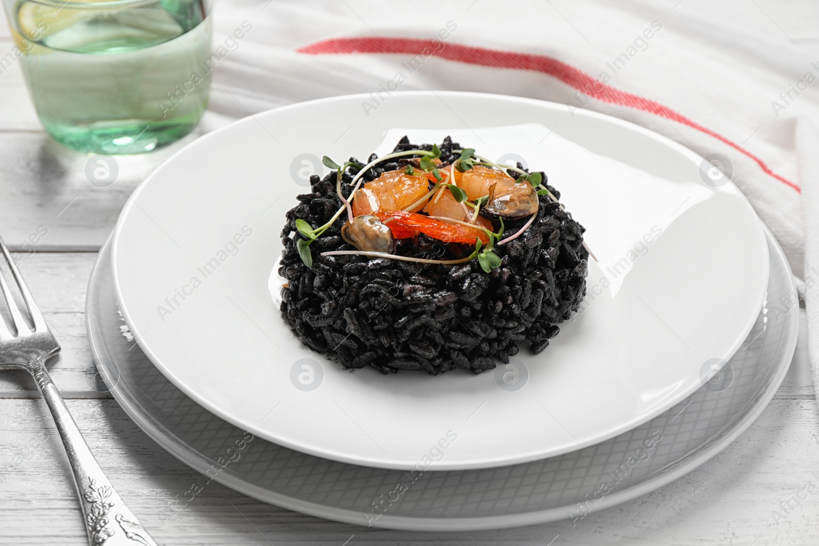 Photo of Delicious black risotto with seafood on white wooden table