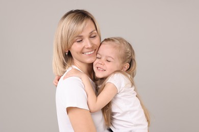 Family portrait of happy mother and daughter on grey background