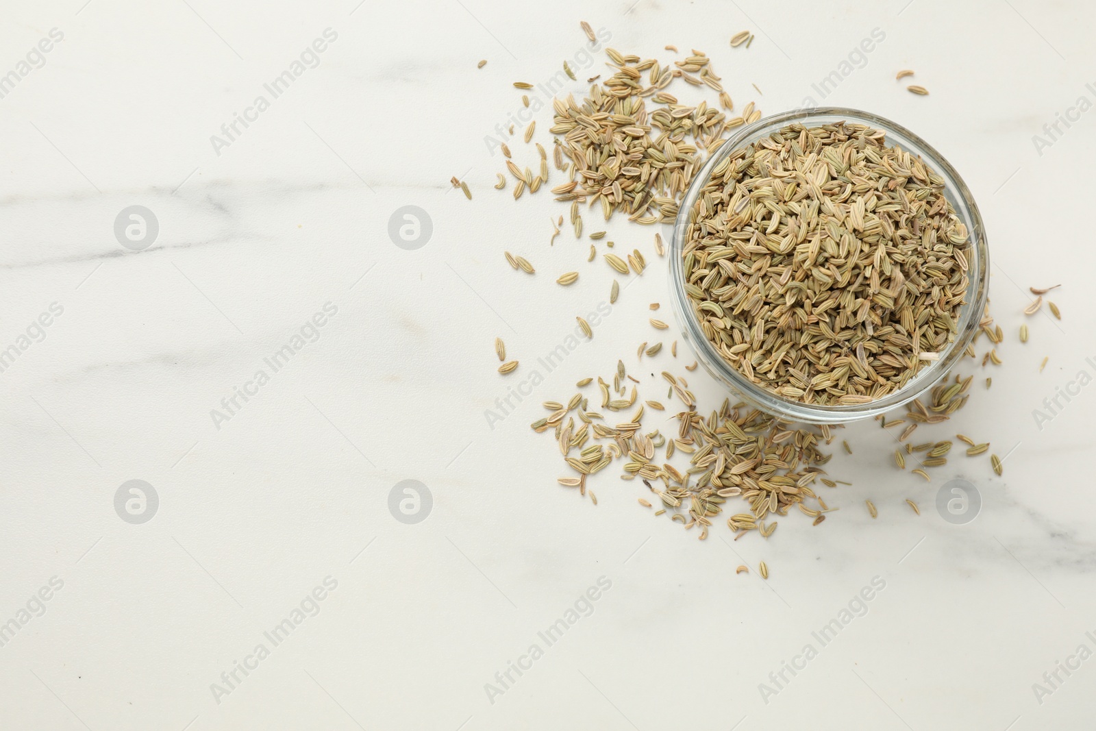 Photo of Fennel seeds in bowl on white table, top view. Space for text