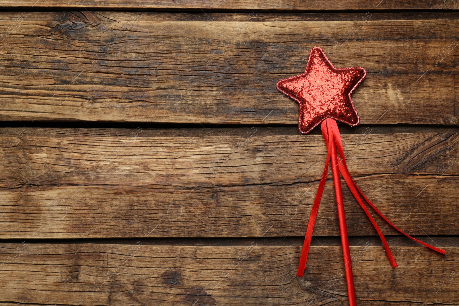 Photo of Beautiful red magic wand on wooden table, top view. Space for text