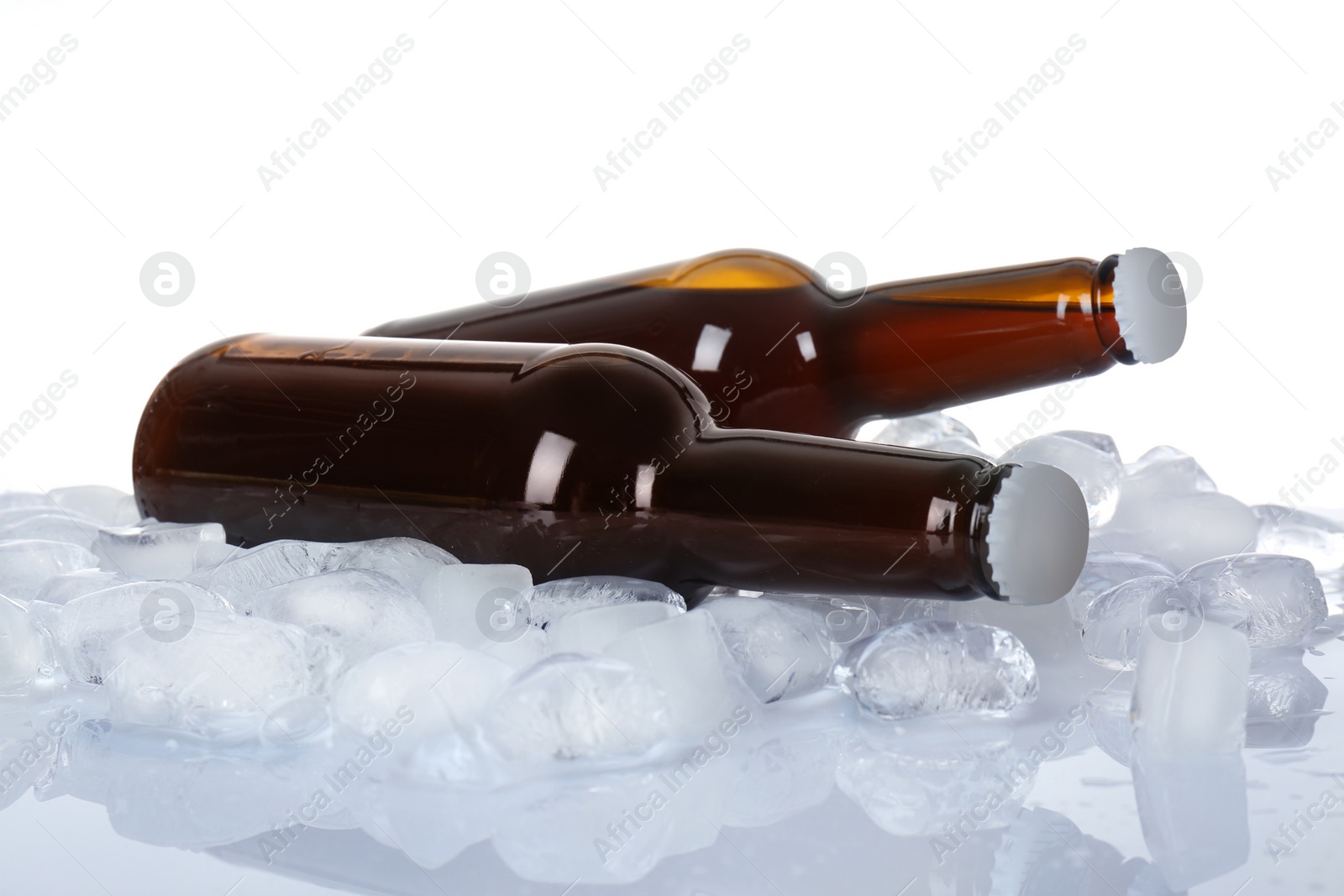 Photo of Bottles of beer on ice cubes against white background