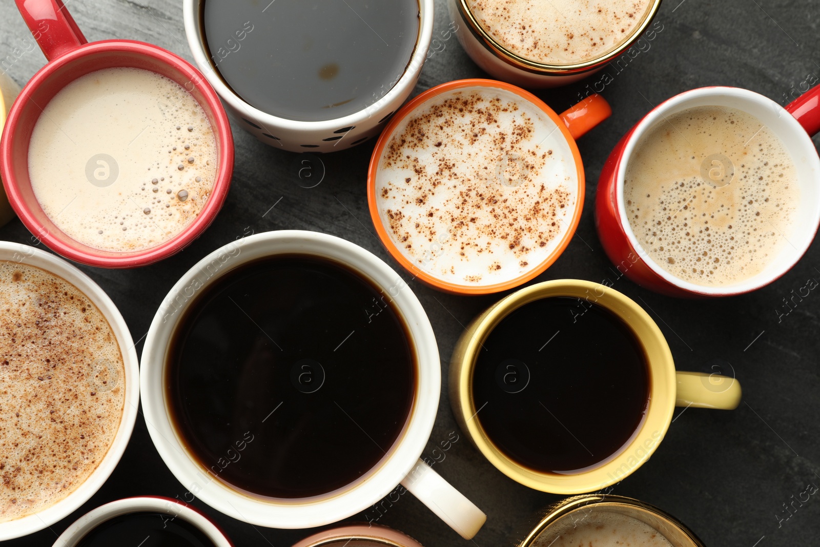 Photo of Many cups of different coffees on slate table, flat lay