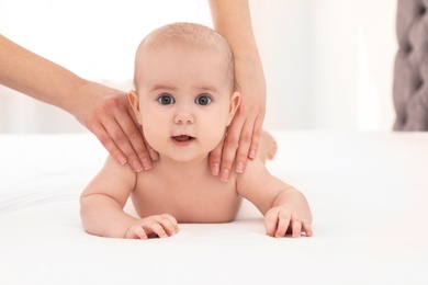 Mother and her cute child on bed indoors, space for text. Baby massage and exercises