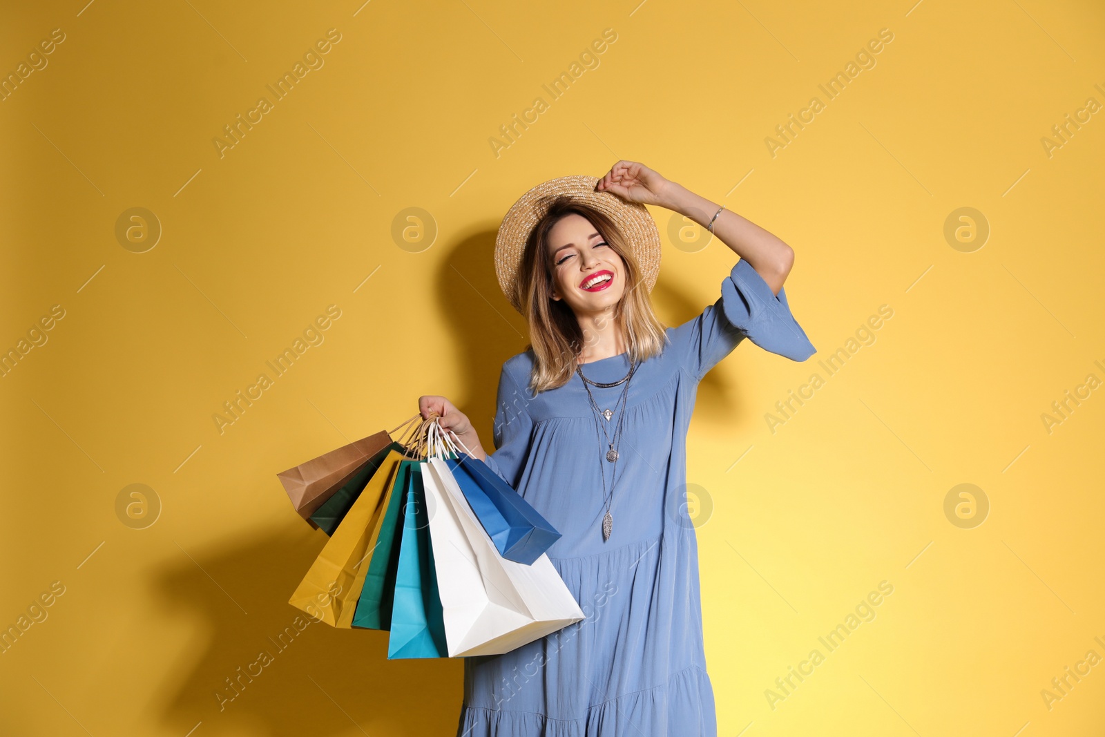 Photo of Beautiful young woman with shopping bags on color background