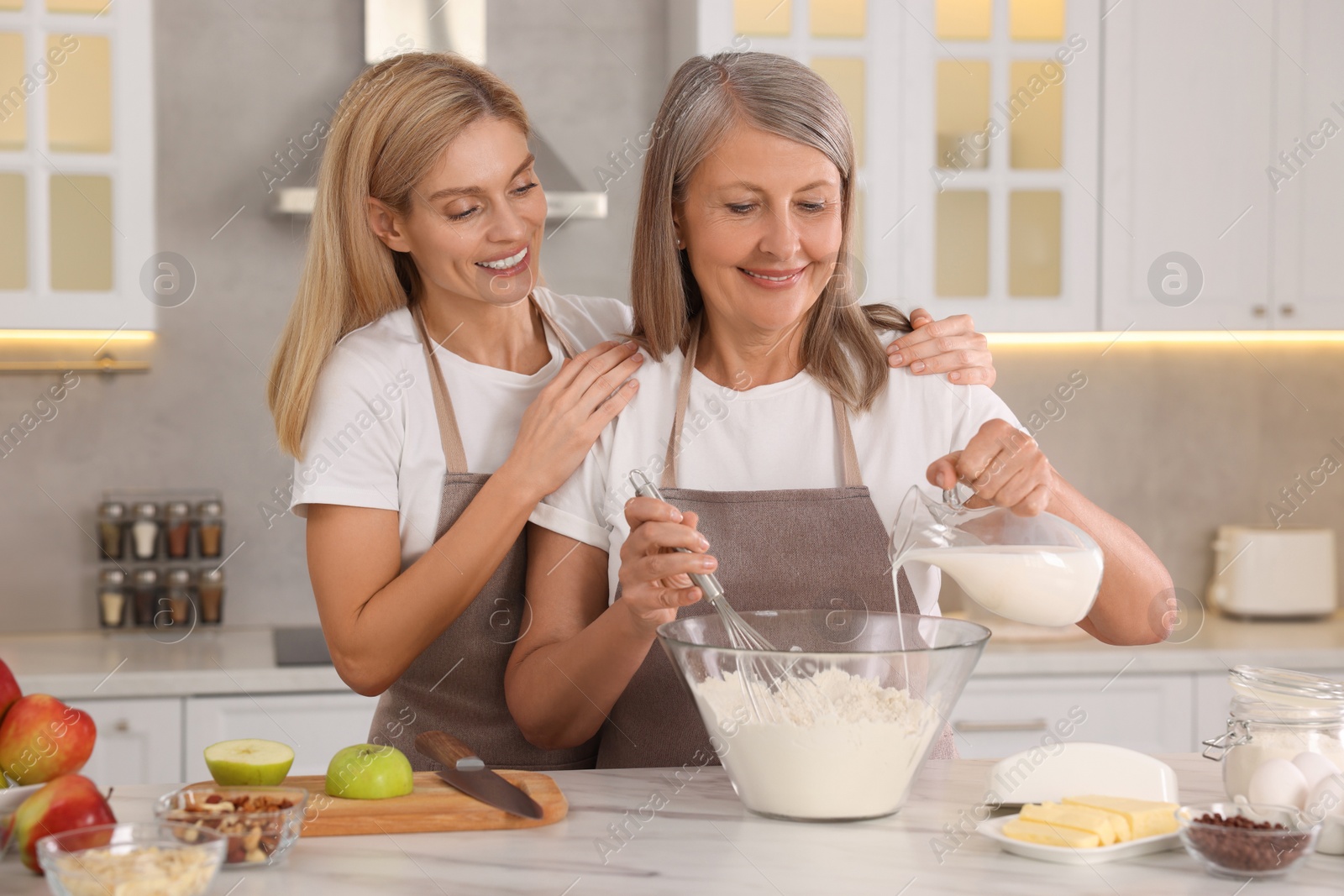 Photo of Happy mature mother and her daughter cooking together at kitchen