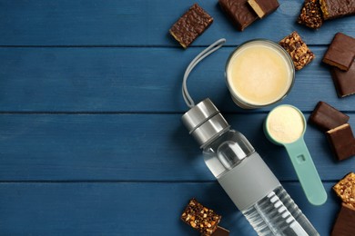 Photo of Different energy bars, water, protein cocktail and powder on blue wooden table, flat lay. Space for text