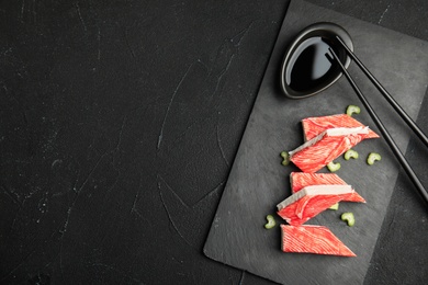 Fresh crab sticks with celery served on black table, top view. Space for text