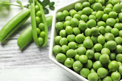 Bowl with green peas on table, closeup