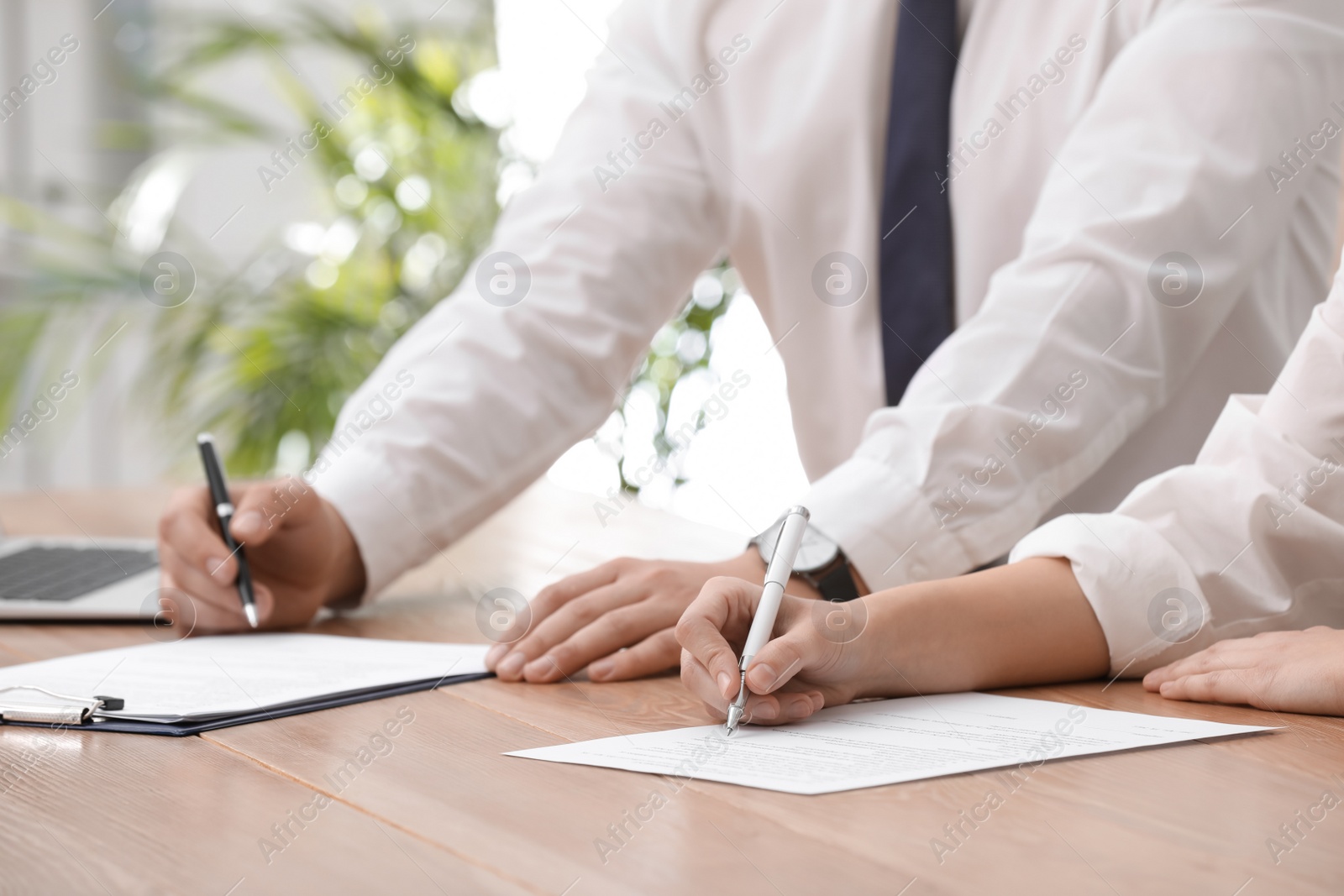 Photo of Woman signing contract at table in office, closeup.