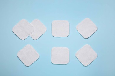 Many cotton pads on light blue background, flat lay