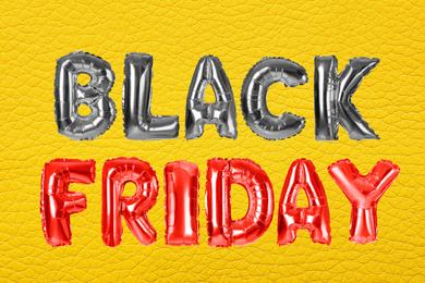 Image of Phrase BLACK FRIDAY made of foil balloon letters on yellow background
