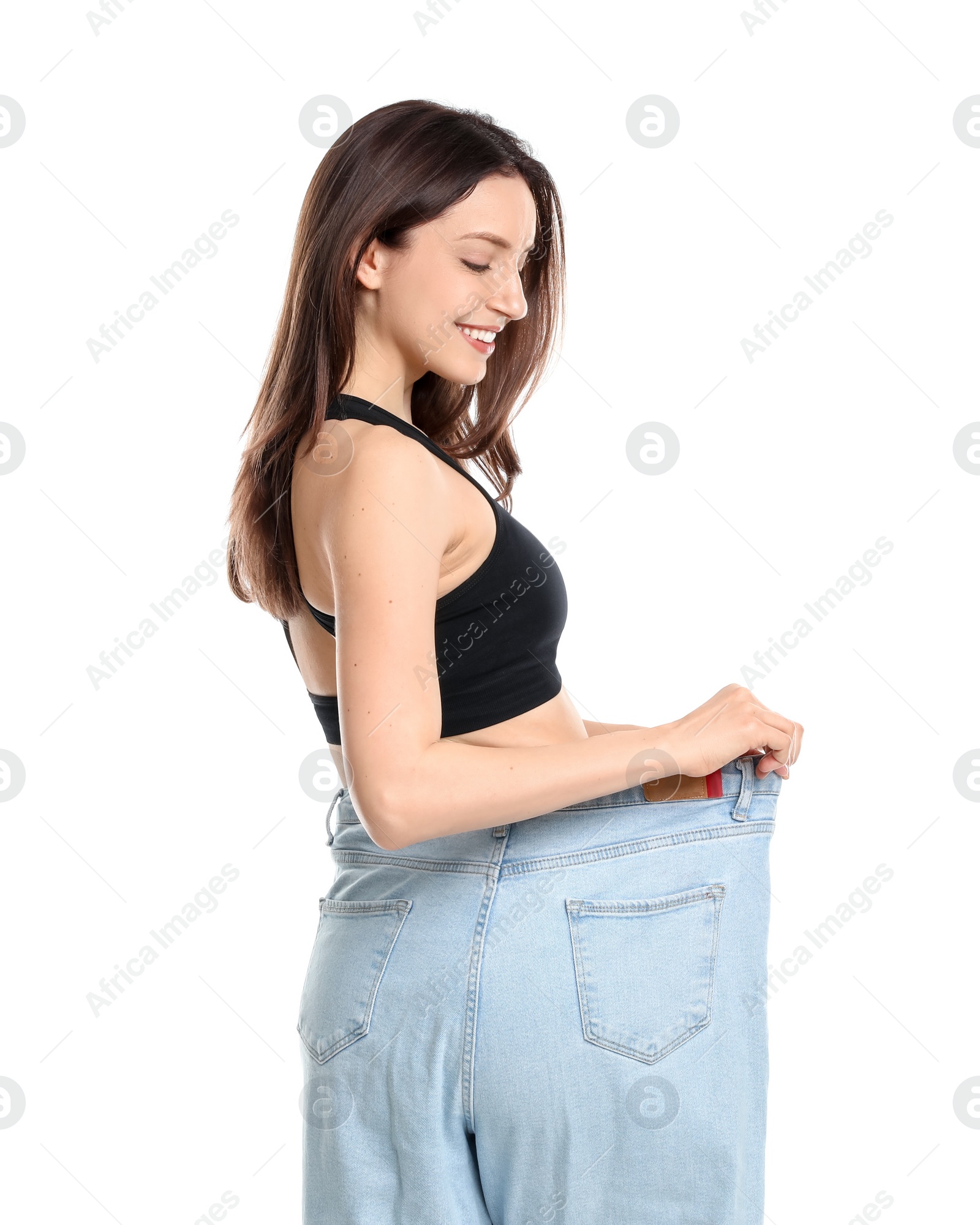 Photo of Happy young woman in big jeans showing her slim body on white background