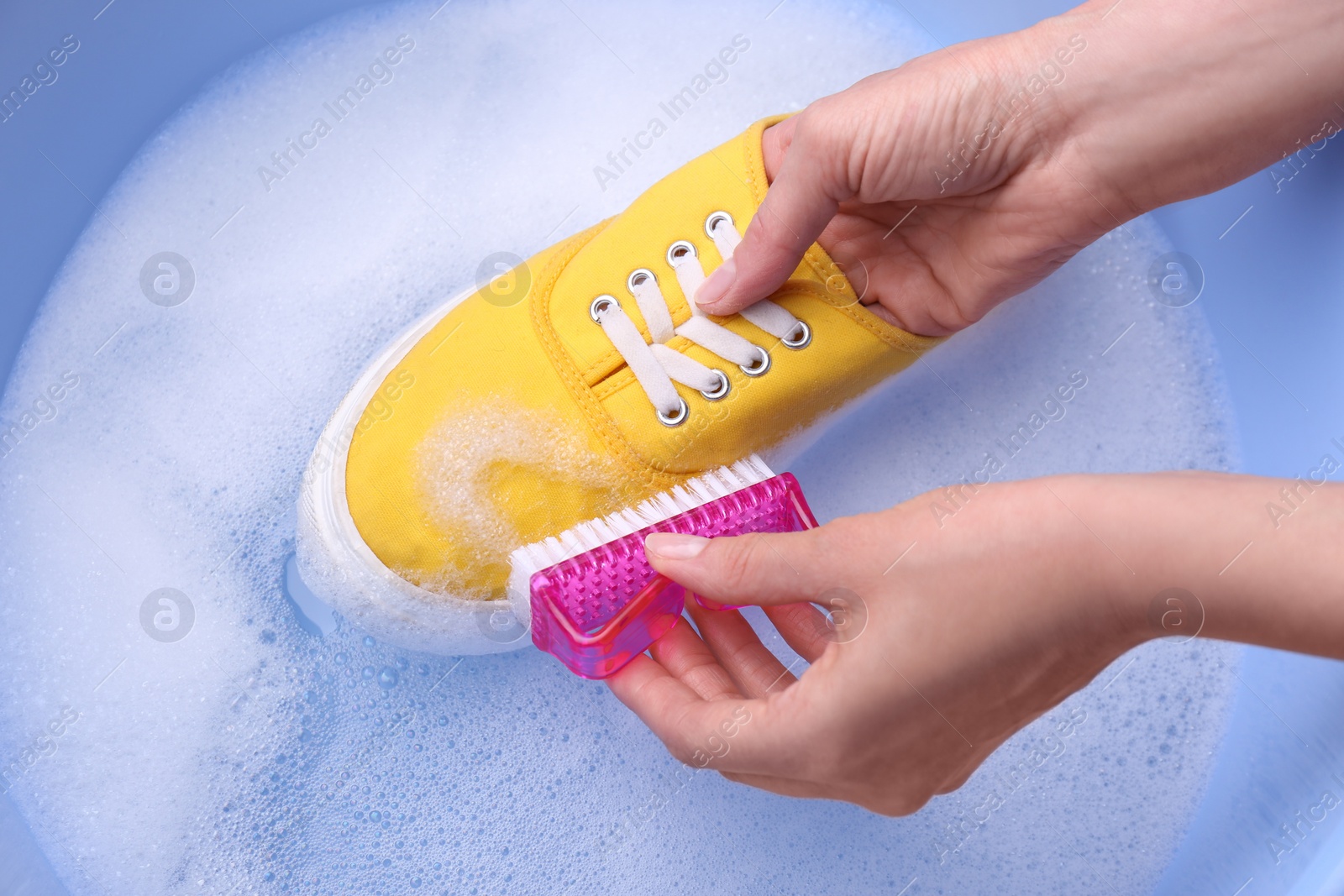 Photo of Woman washing shoe with brush in basin, closeup