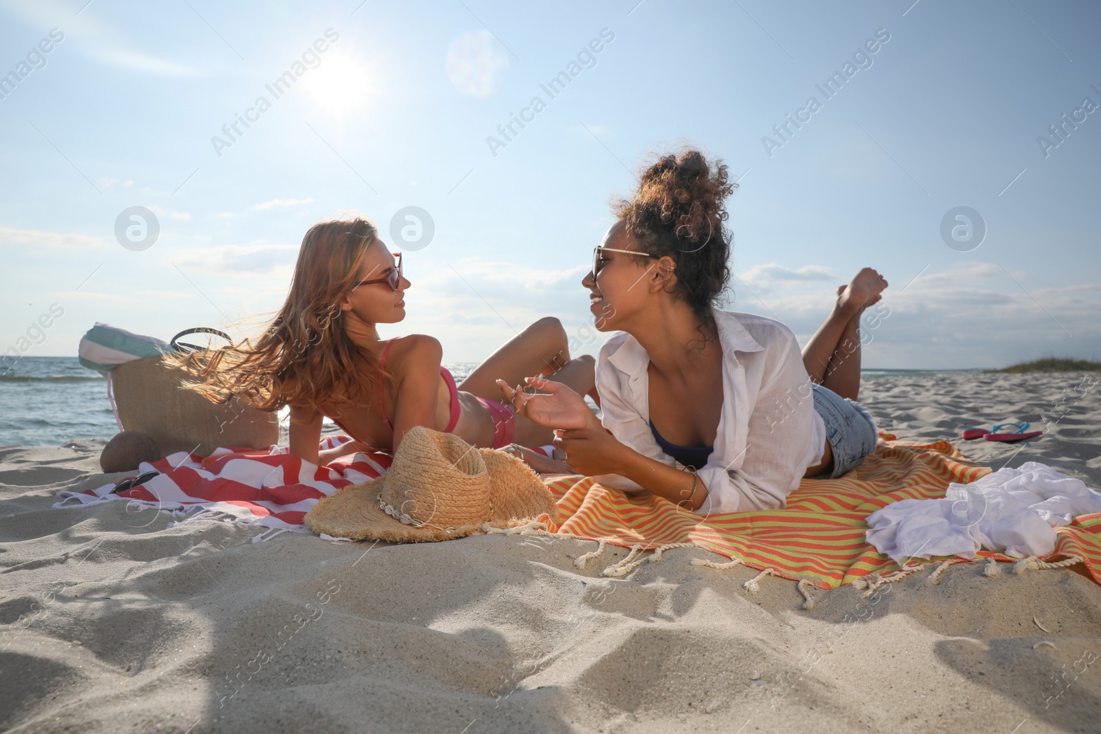 Photo of Friends lying on beach towels near sea