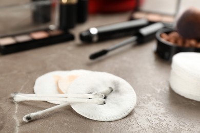 Photo of Dirty cotton pads, swabs and cosmetic products on grey table